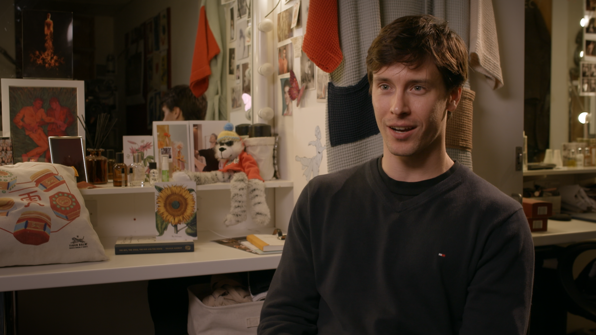 Calvin Richardson sits in his dressing room in front of a mirror, he is wearing a dark blue jumper. 
