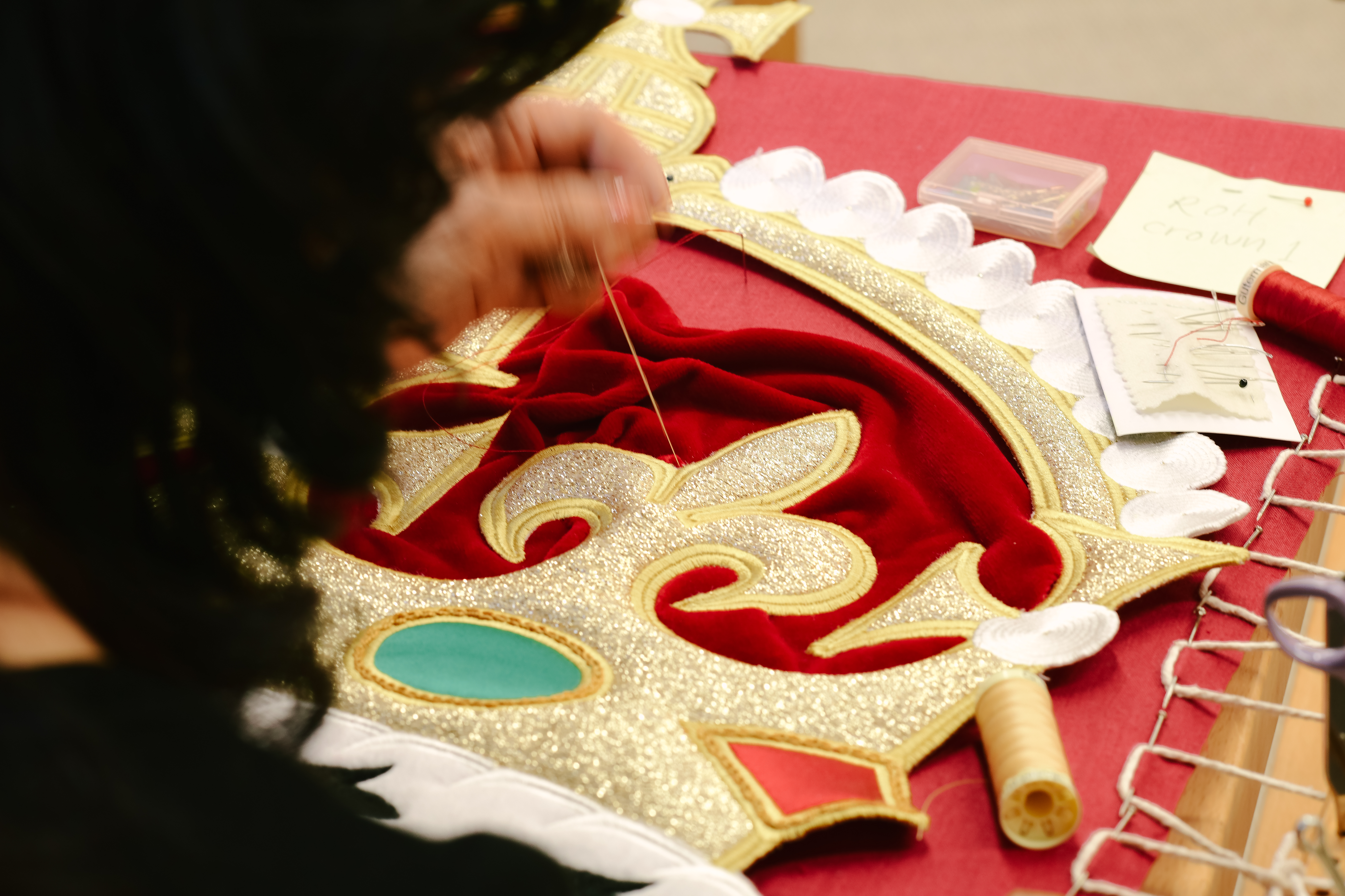 An embroiderer from the Royal School of Needlework sews the crown onto the new Royal Opera House stage curtains. (2 of 3)