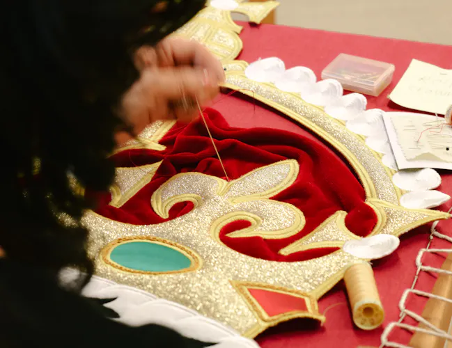 An embroiderer from the Royal School of Needlework sews the crown onto the new Royal Opera House stage curtains. (2 of 3)