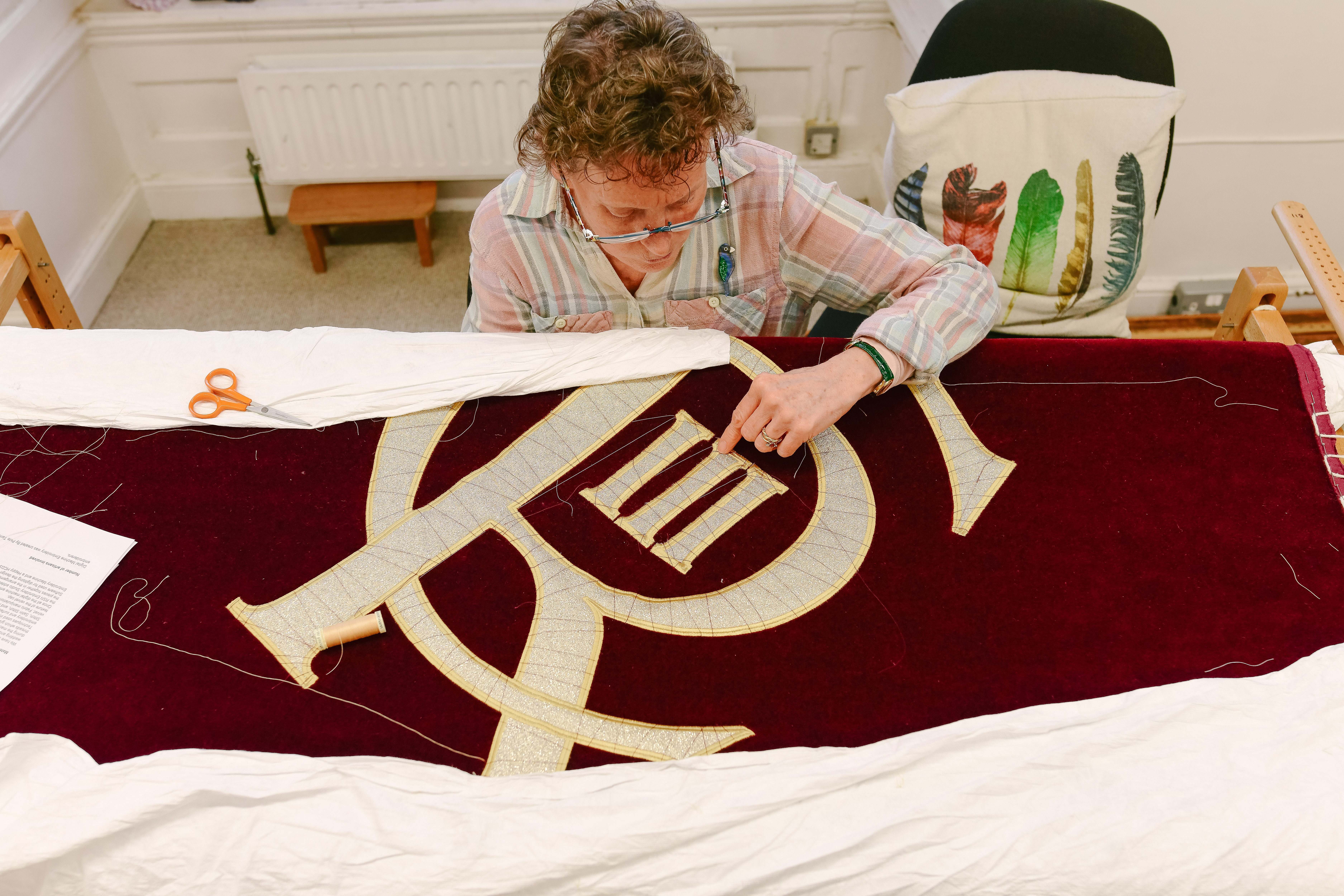 An embroiderer from the Royal School of Needlework sews King Charles III's insignia onto the new Royal Opera House stage curtains. (1 of 3)