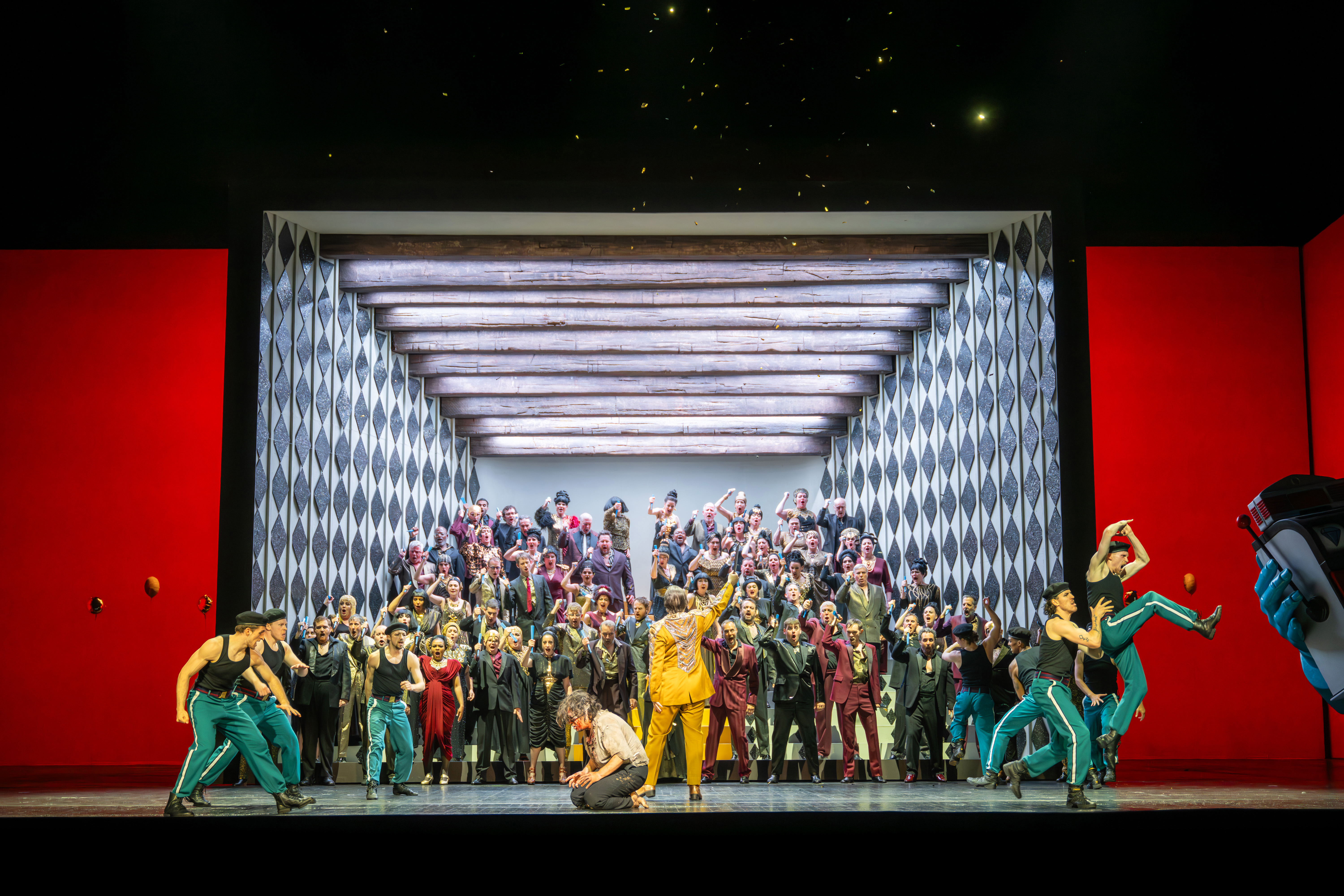 A large group of people in colourful outfits stand in and spill out of a small stage. (1 of 6)