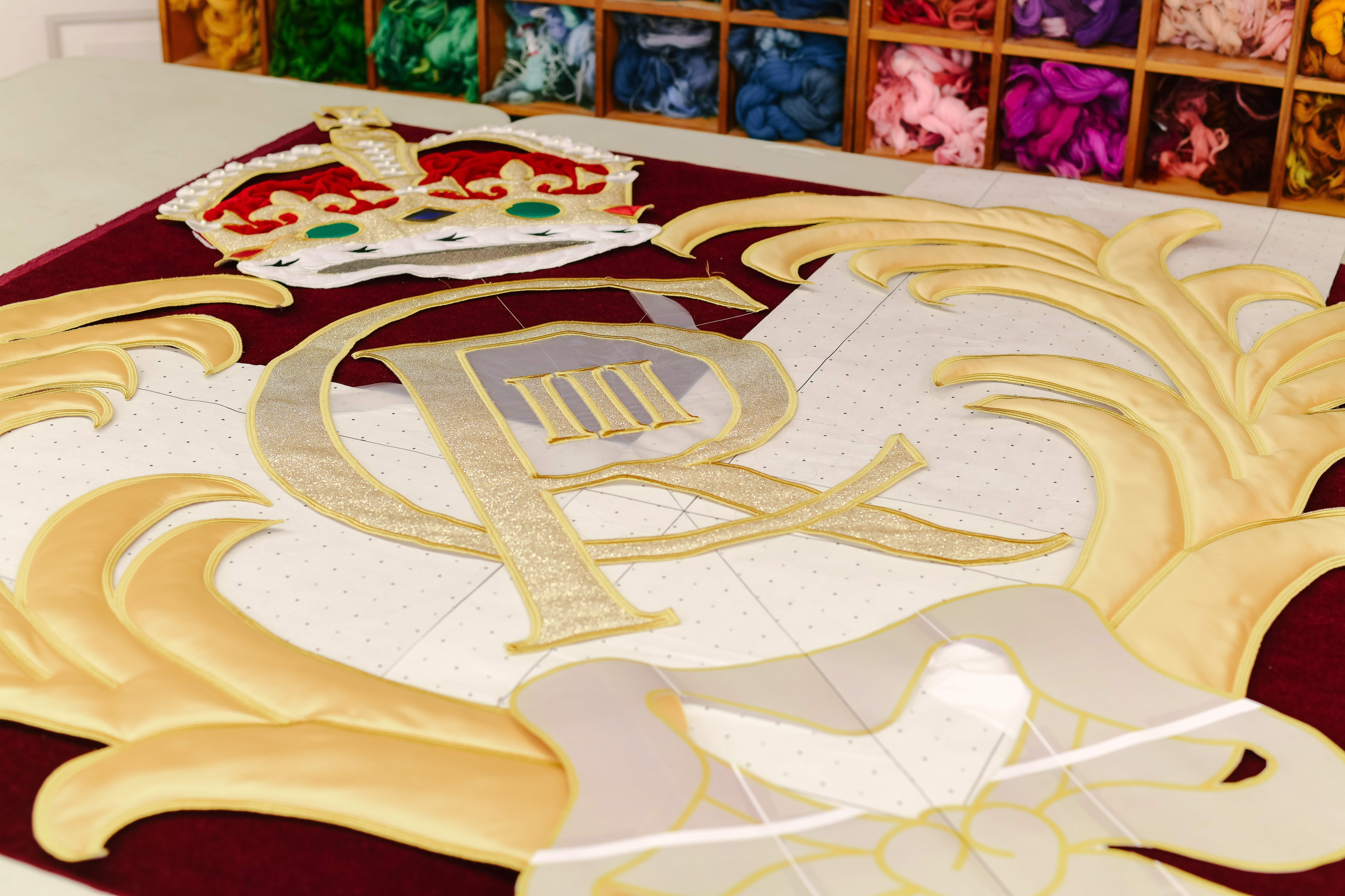 King Charles III's insignia for the new Royal Opera House stage curtains lay on a table at the Royal School of Needlework. (3 of 3)