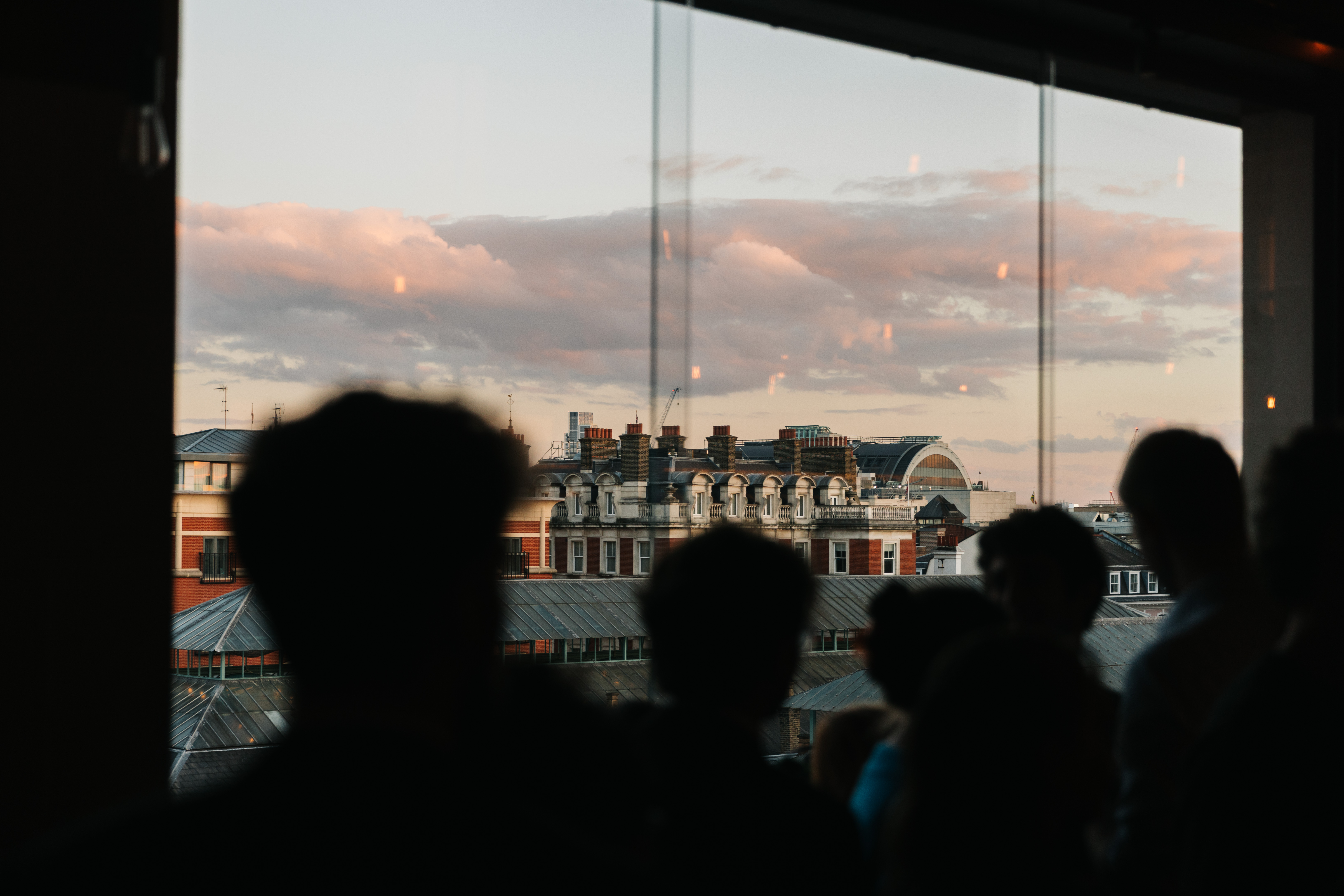 A group of people are in a shadow looking out over the piazza of Covent Garden. They are on the Cicoria Terrace within the Royal Opera House for a Young RBO night. (3 of 9)