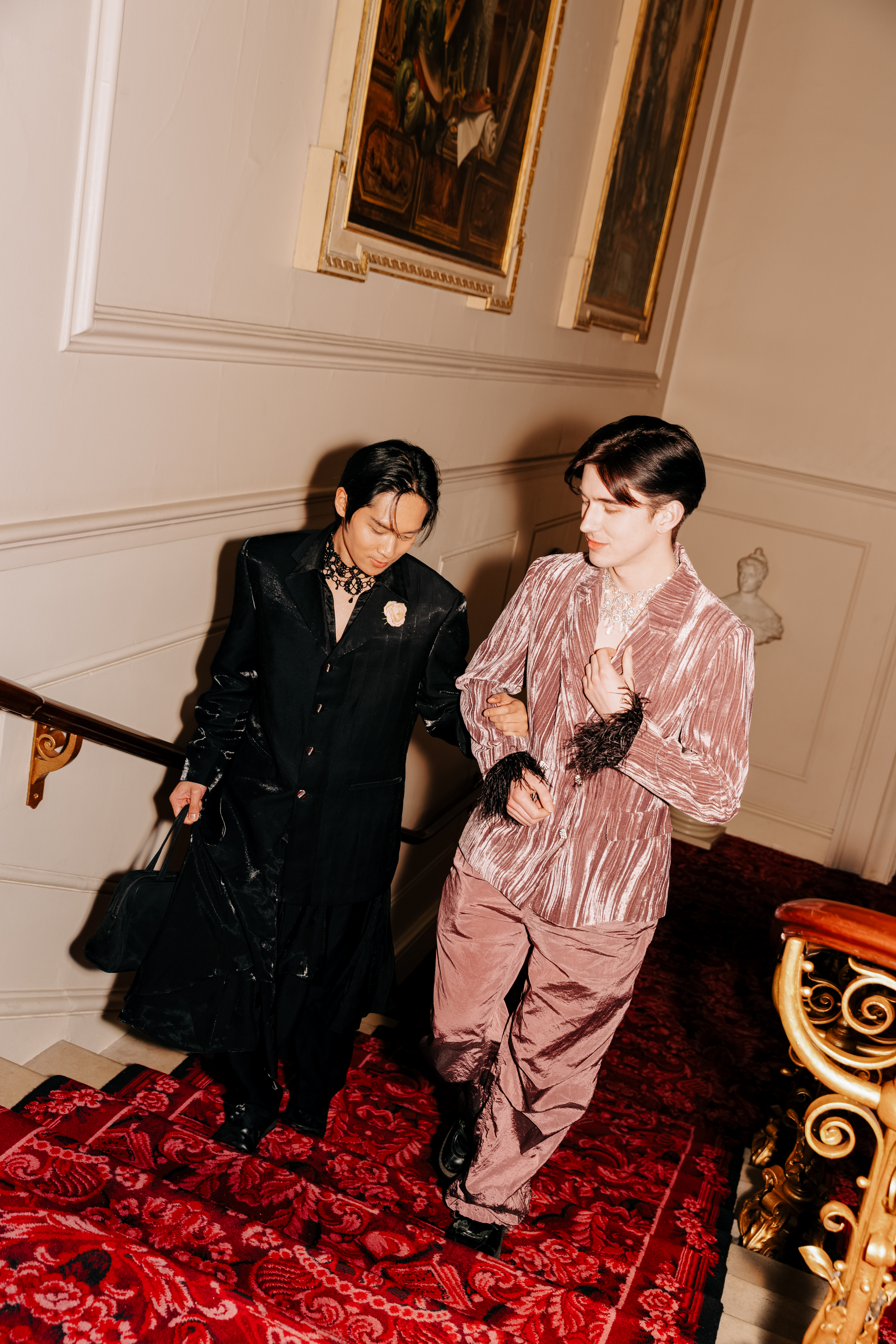 Two people walk up red decorative stairs of an ornate hallway. (5 of 9)
