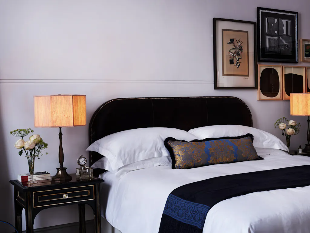 A black velvet bed with white and navy blue bedding.