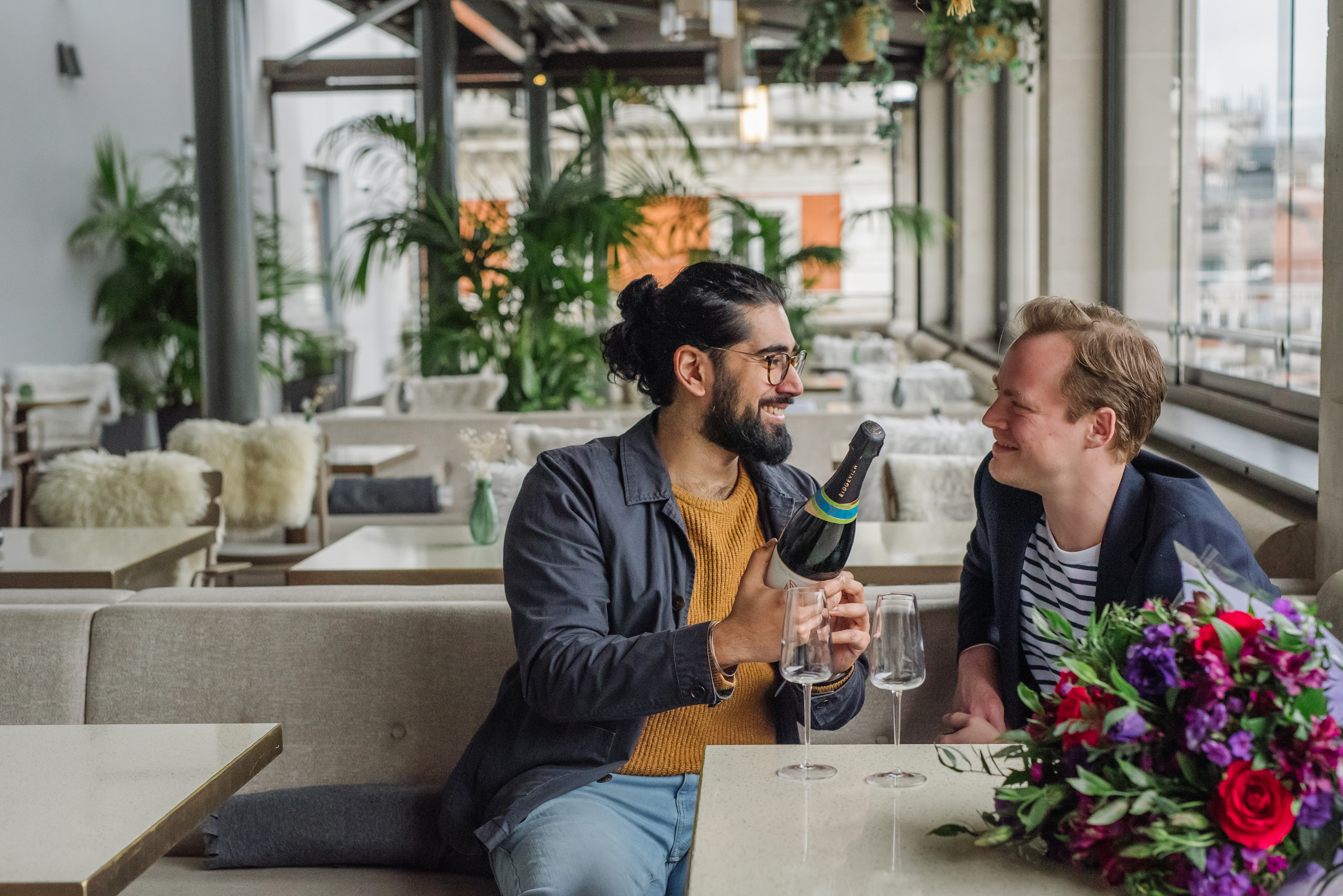 A couple smiling at each other in a rooftop restaurant.