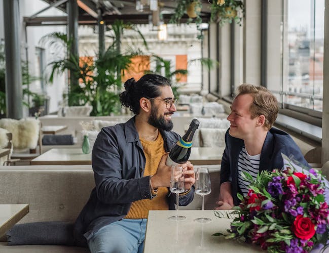 A couple smiling at each other in a rooftop restaurant.