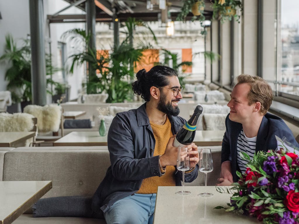 A couple smiling at each other in a rooftop restaurant.