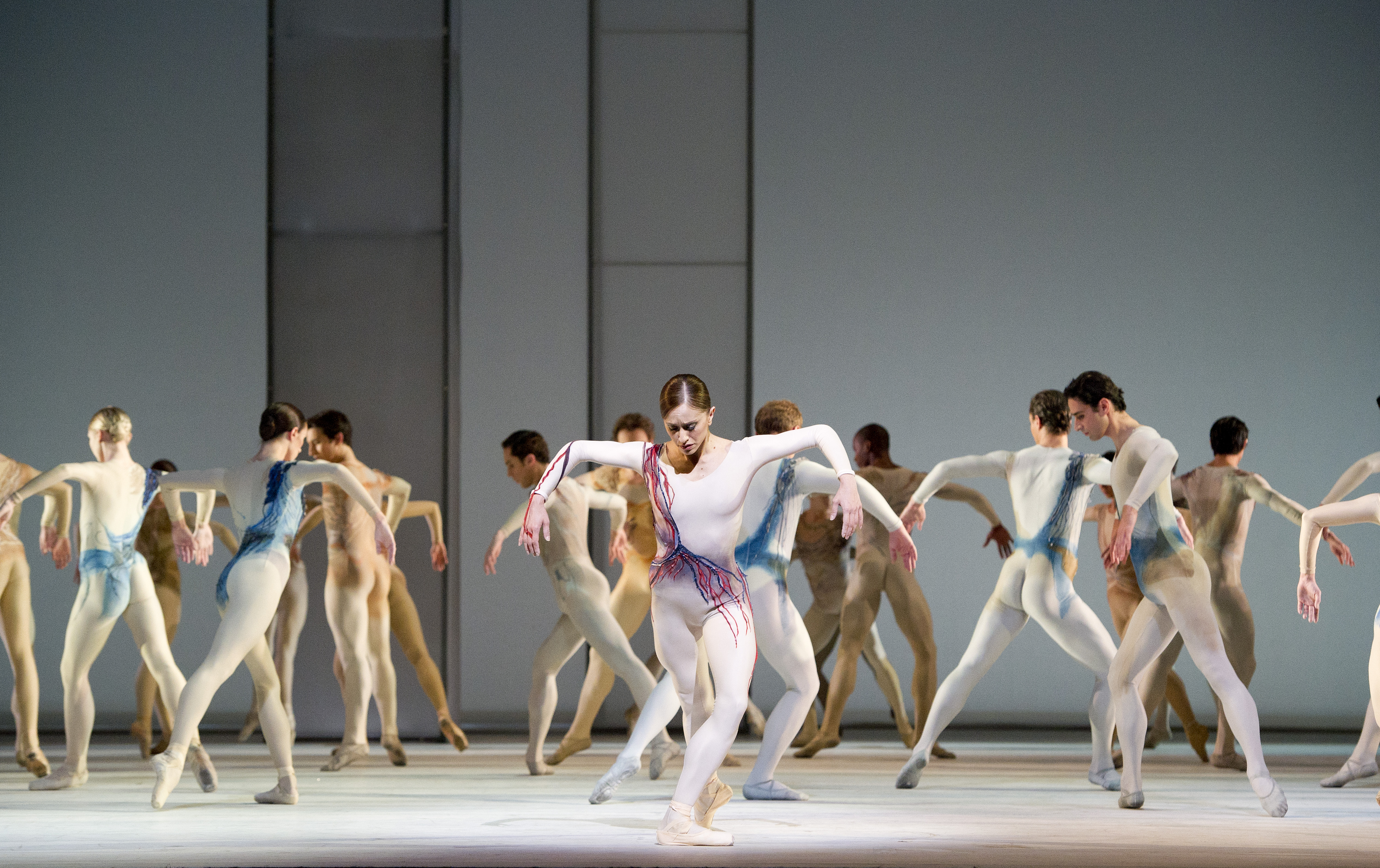 Dancers in white costumes stand still on stage