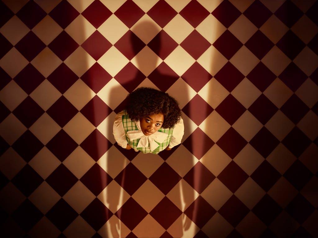 Opera singer Pretty Yende is photographed as Semele, a character in the opera of the same name. Semele gazes up at an unseen person who casts a looming shadow over her.