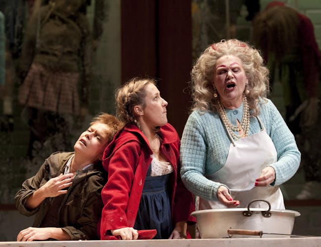 A boy and girl annoy their mother who is cooking