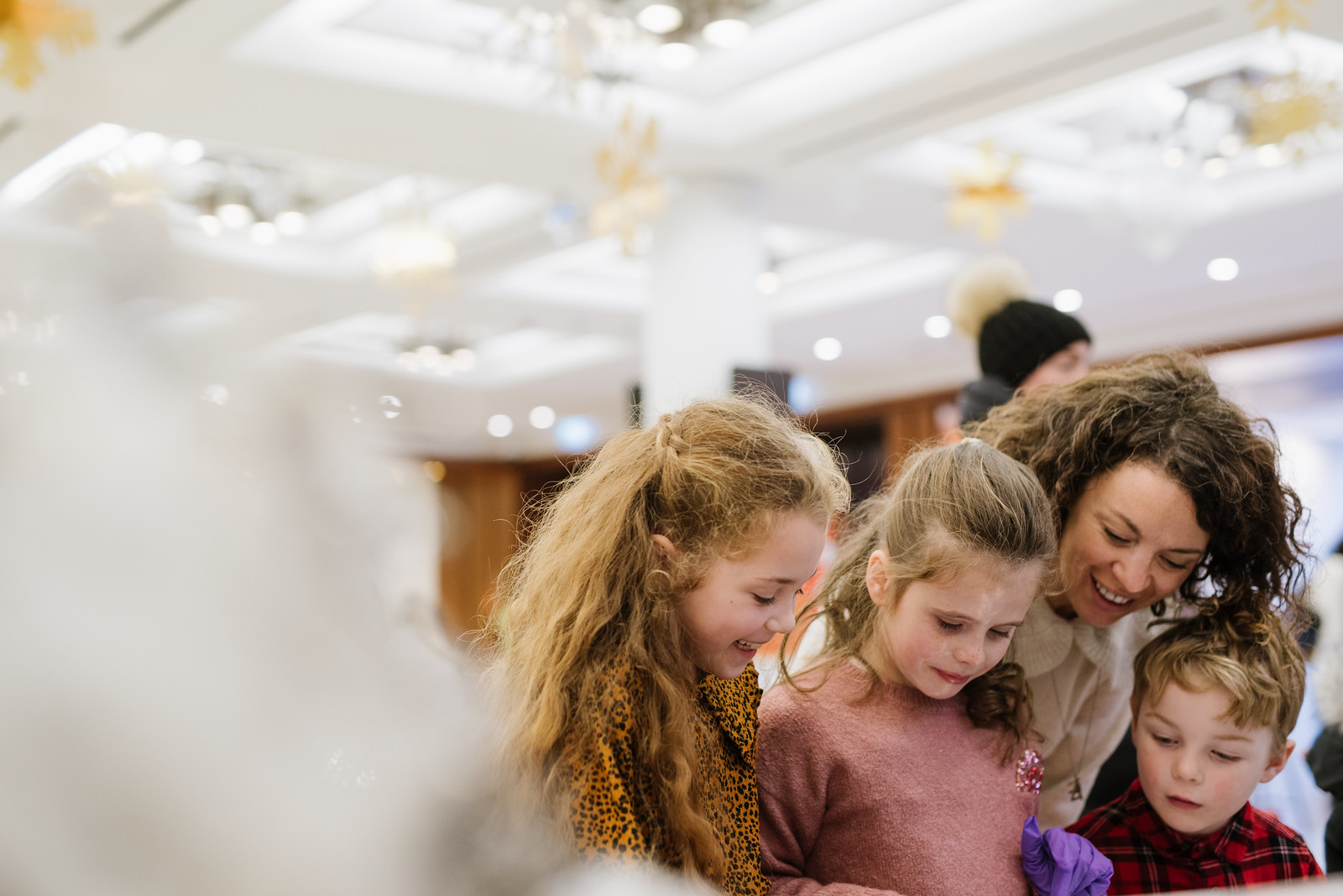 A woman with a three small children smiling at an event.