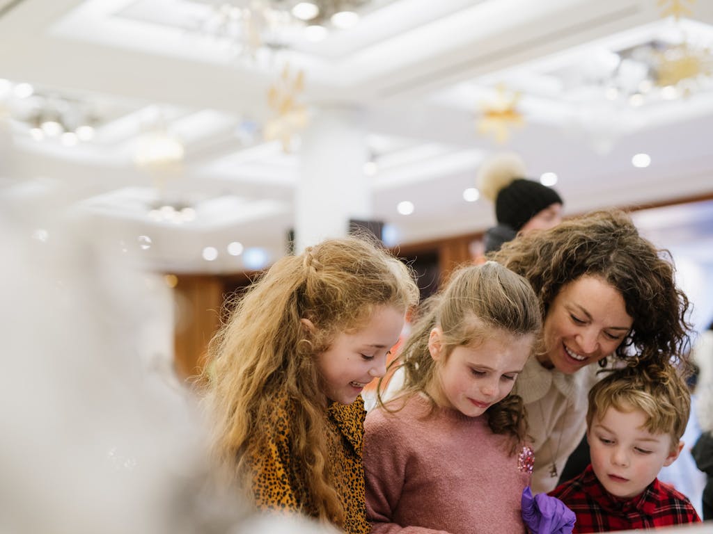 A woman with a three small children smiling at an event.