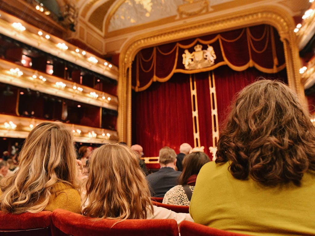People sitting in the audience in the main auditorium of the Royal Opera House.