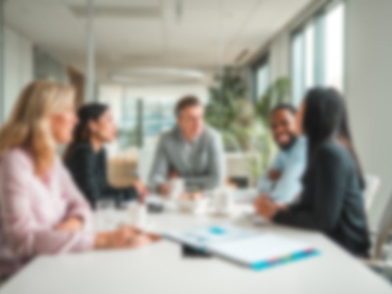 Blurred image of 5 people working together at a table.