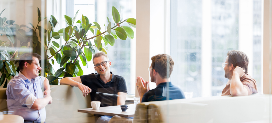 Collega's van RS Finance in gesprek met een kop koffie aan tafel.