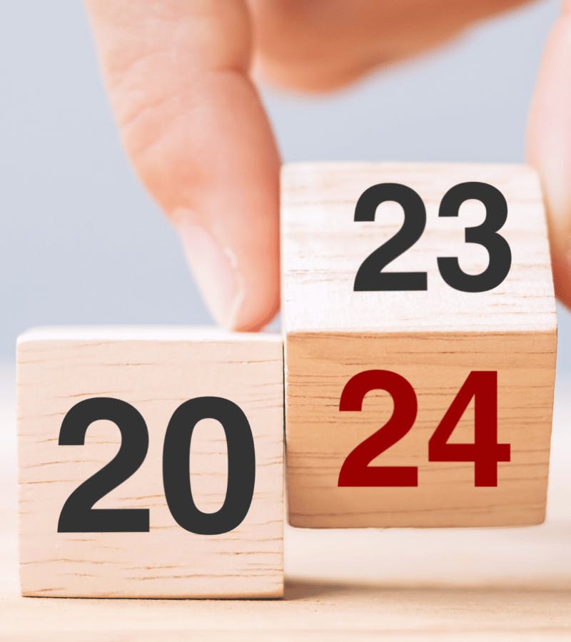 Twee houten blokjes met de getallen 20 en 23 erop en een hand die het tweede blokje kantelt zodat het getal 24 in beeld komt.
