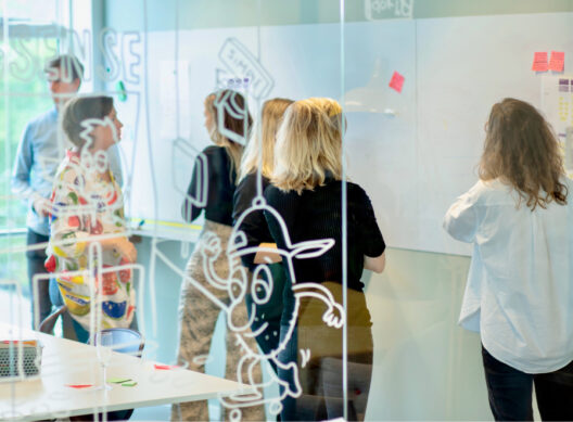 Een groep mensen in een brainstormsessie met post-it briefjes en een groot whiteboard.