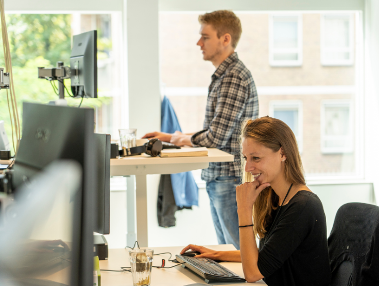 Twee medewerkers van RS Finance staand en zittend aan het werk.