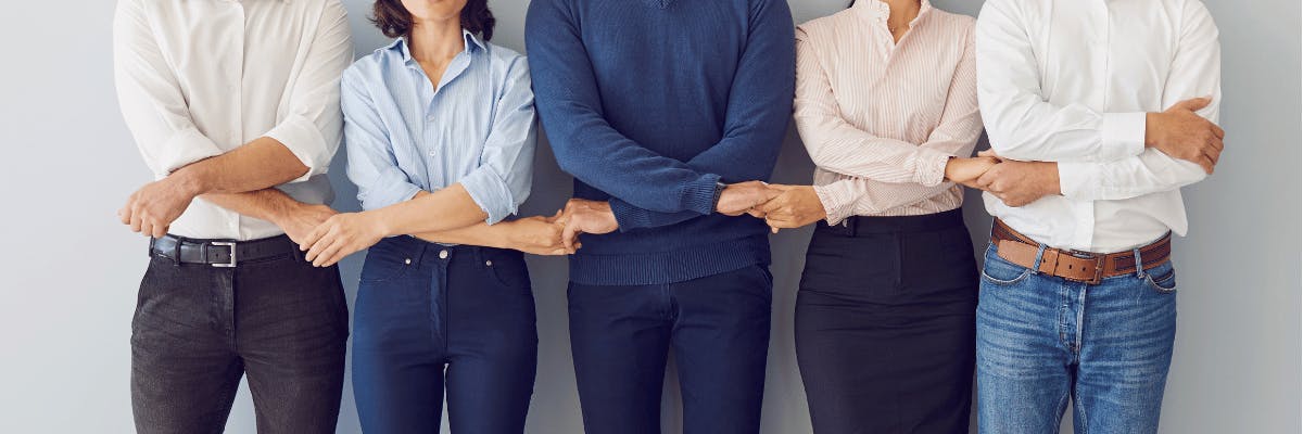 Vijf mensen in casual zakenkleding staan op een rij en houden elkaars handen kruislings vast