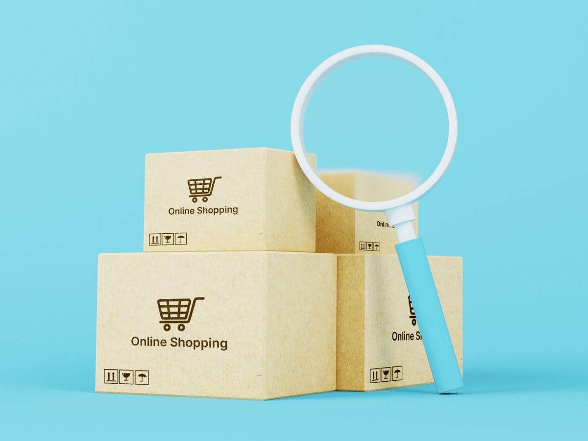 Vergrootglas en "online shopping" dozen op blauwe achtergrond
