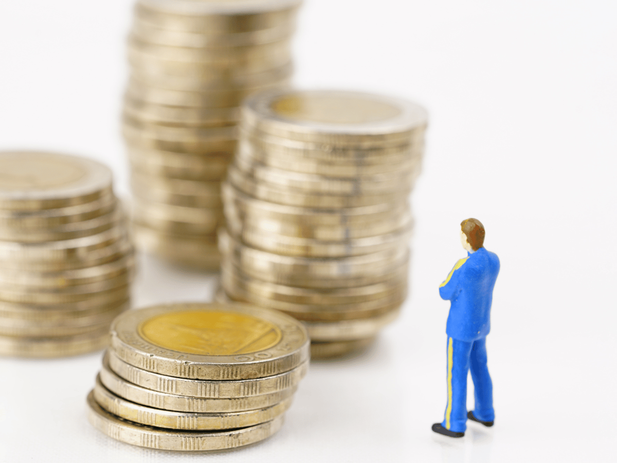 Een poppetje van een man staat te kijken naar vier stapels munten in verschillende hoogtes.