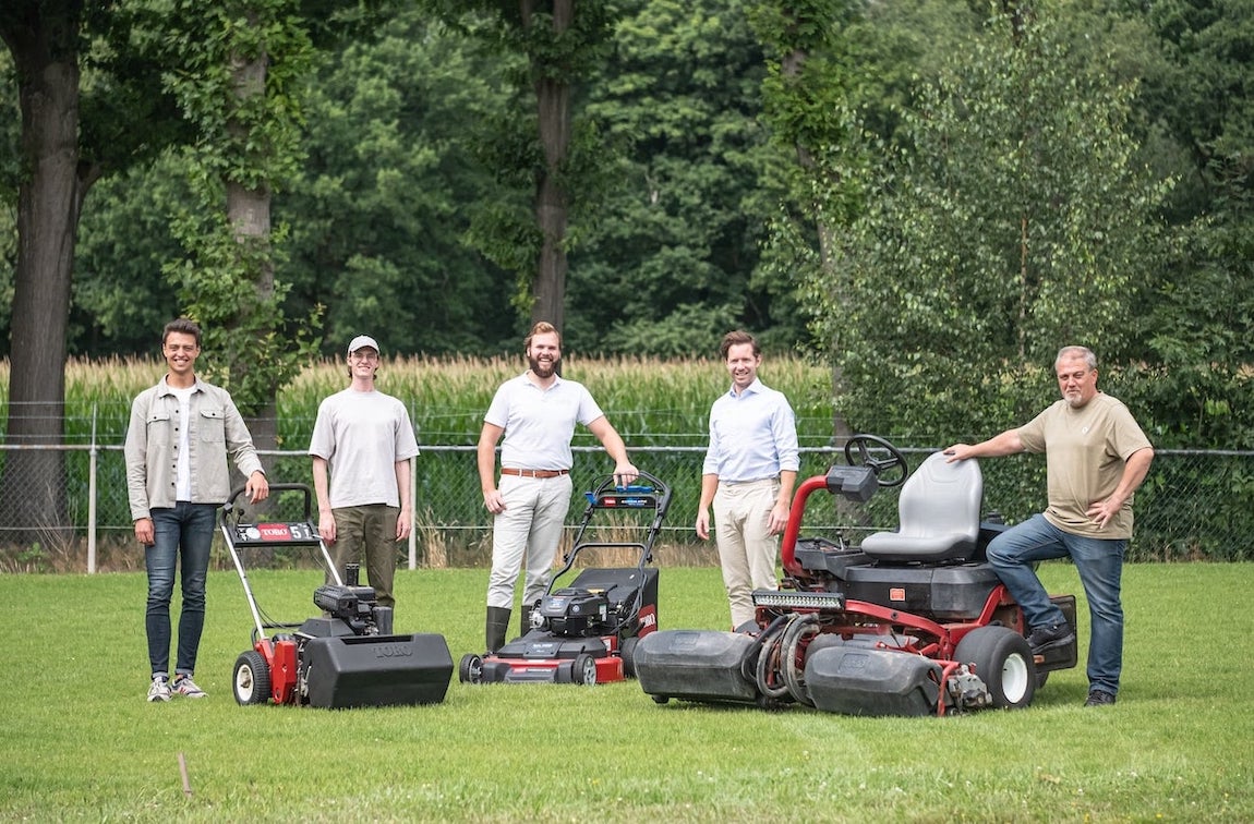 Het team van Moowy staat op het grasveld bij een set geavanceerde grasmaaimachines