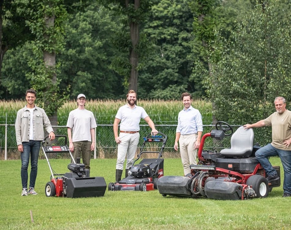 Het team van Moowy staat op het grasveld bij een set geavanceerde grasmaaimachines