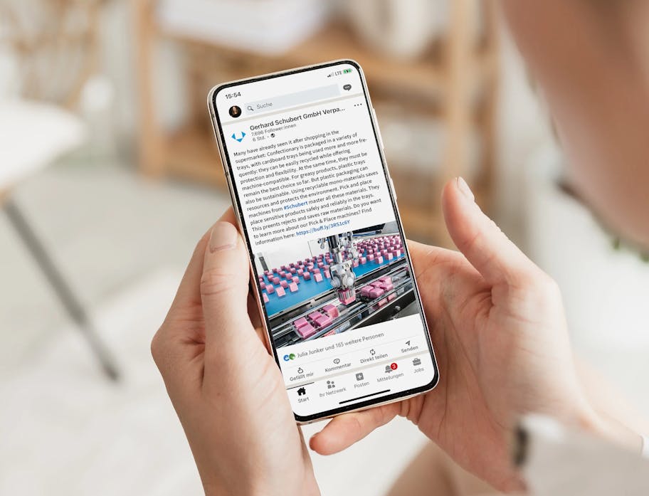 View over the shoulder of a woman looking at a LinkedIn post from the Schubert company