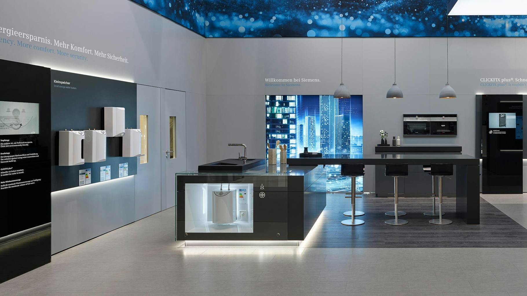 The photo shows a futuristic kitchen in a showroom, with descriptions on the wall and a ceiling made of LED panels