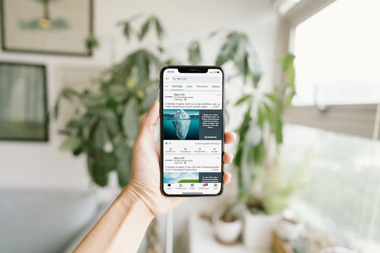 The image shows a smartphone being held in hand, displaying an ad created for a digital campaign for Manz AG.