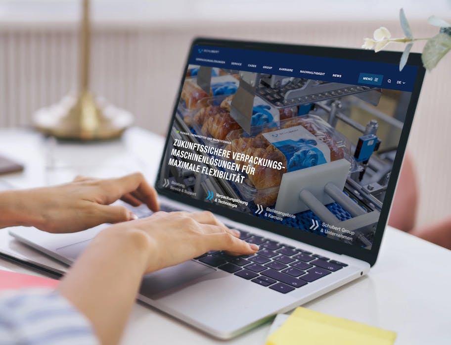 A woman is sitting in front of a laptop, her fingers on the keyboard, looking at the user interface of the Schubert company.