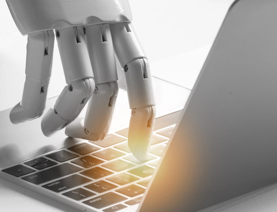 Roboterhand schreibt auf einem Laptop eine Mail an eine content marketing agency.