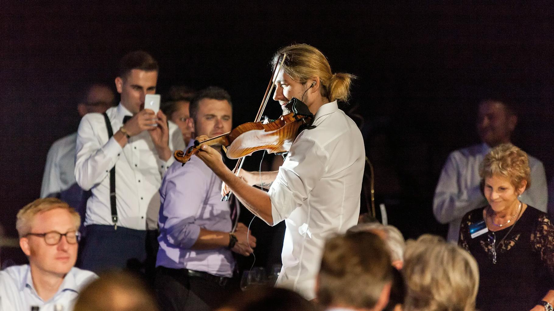 David Garret spielt, umkreist von Menschen, auf einem corporate event, Geige.