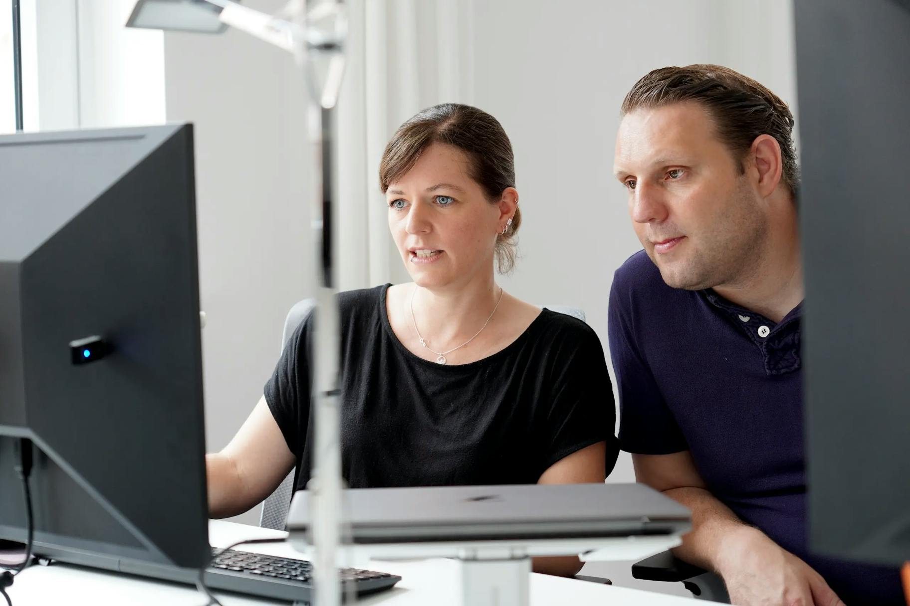 Digital Consultants Bettina und Christoph im Gespräch vor einem Monitor