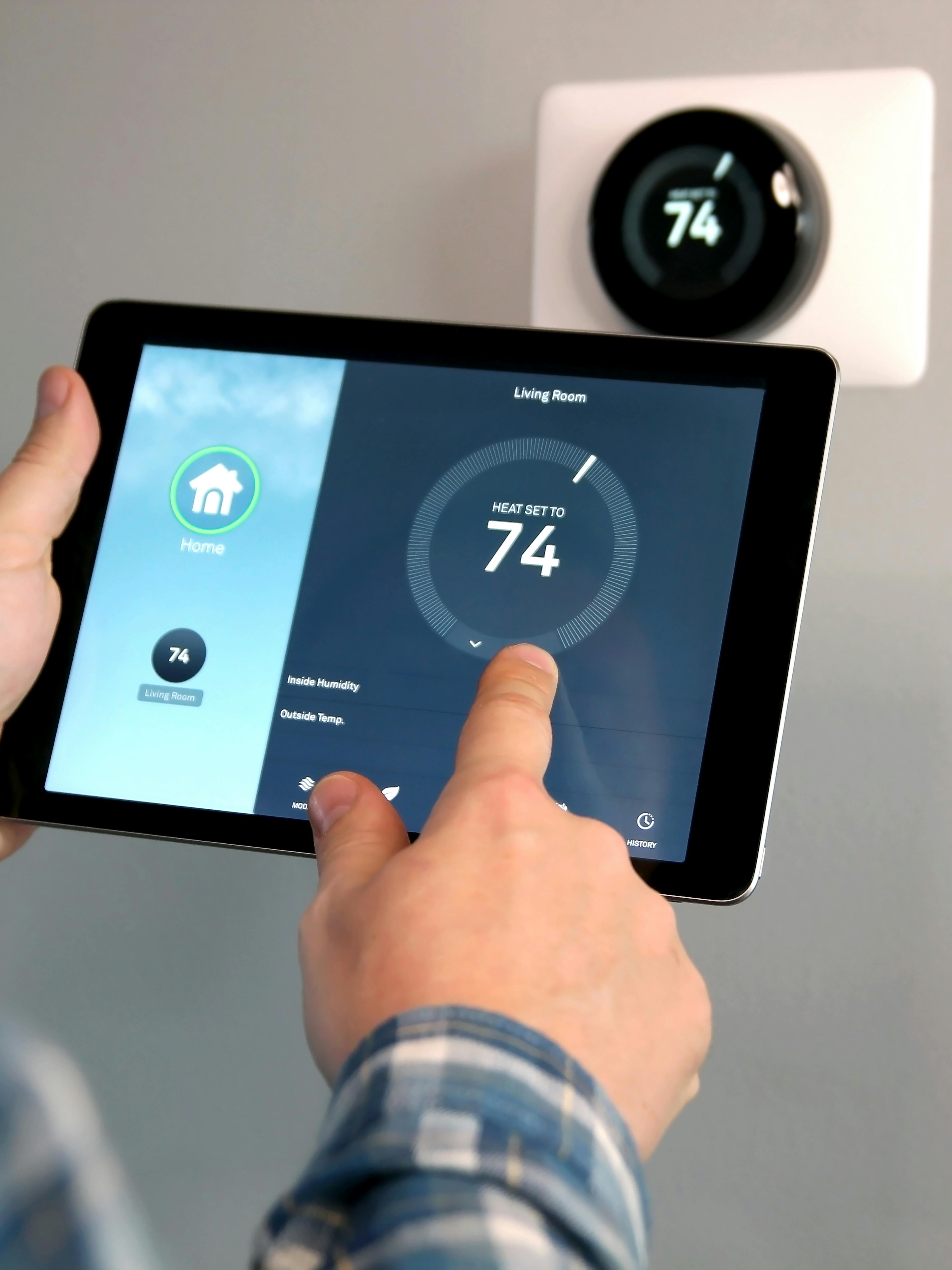 Man is Adjusting a temperature using a tablet with smart home app in modern living room