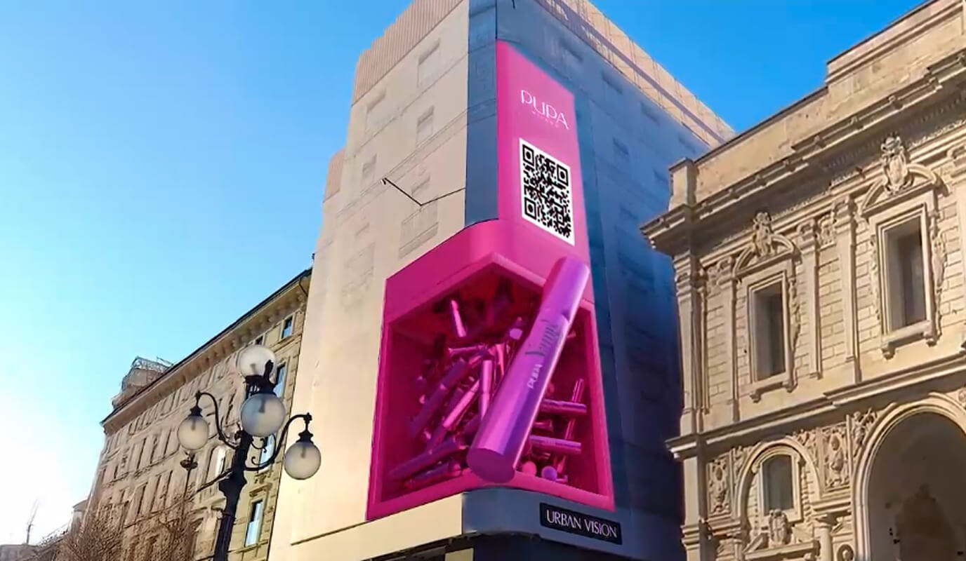 An AR billboard in Via Mercanti lets users scan a QR code to watch nearby buildings blush in vibrant fuchsia.