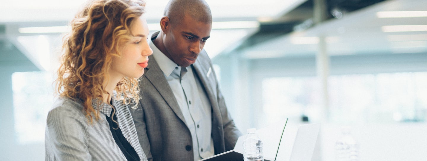 A man and a woman working with their laptops