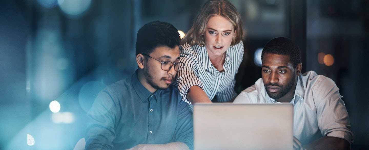 Two men and a woman are watching a computer screen and discussing something important.