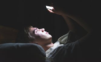 person scrolling through phone in bed