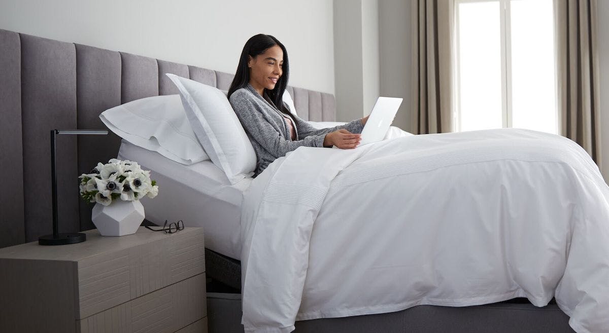 person using laptop on saatva lineal adjustable base