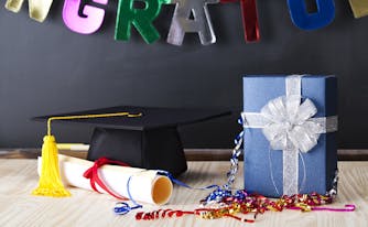 graduation cap and diploma next to graduation gift in a wrapped box