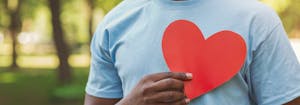 person holding paper heart up to chest