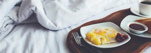 breakfast in bed featuring eggs, toast, and coffee on a tray