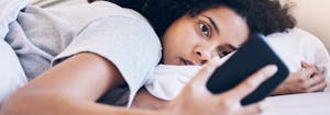 person staring at phone in bed