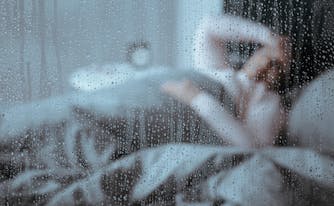 person sleeping in bed with rain outside