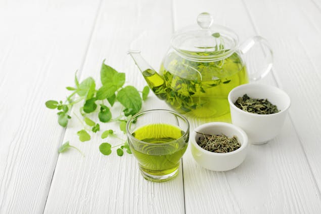 pot and cup of green tea with two bowls of green tea leaves