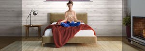 person meditating on bed with red blanket