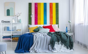 kindercore bedroom with yellow, green, gray, red, and pink pillows on top of bed