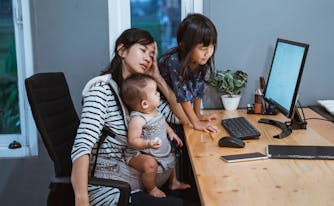 tired mom at computer with two children